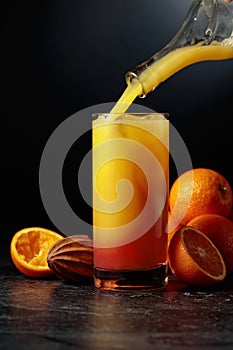 Cocktail Tequila Sunrise with ice and grenadine on a black background