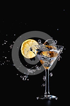 Cocktail water drink splash in the glass with lemon Isolated on black