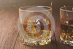 Cocktail from whisky with cherry in two glasses on a wooden back