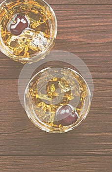 Cocktail from whisky with cherry in two glasses on a wooden back