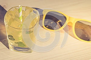 cocktail and yellow sunglasses/cocktail and yellow sunglasses on a light wooden background