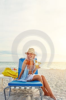 Cocktails on the beach yes please. an attractive young woman lounging on the beach and enjoying a cocktail.