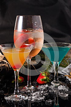 Cocktails on a black background decorated with ice and strawberries