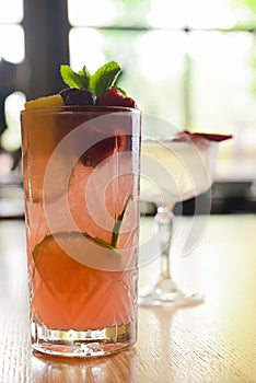 Cocktails with fruits and berries served on a wooden table in restaurant or bar. Alcoholic beverage