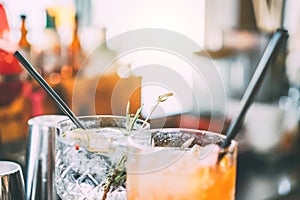 Cocktails served on bar counter prepared with gin, rosemary and orange juice - Drink, nightlife, lifestyle concept