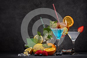 Cocktails set. Glasses with various cold  beverages, bar tools on dark grey background with copy space. Cocktail bar