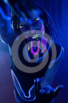 Cocky Girl with Dreadlocks in Ultraviolet neon light with Foggy Background. Bodyart