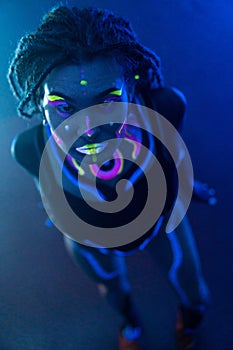 Cocky Girl with Dreadlocks in Ultraviolet neon light with Foggy Background. Bodyart