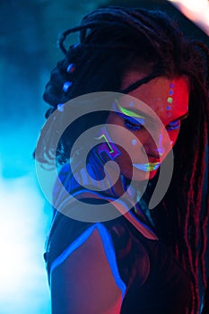 Cocky Girl with Dreadlocks in Ultraviolet neon light with Foggy Background. Bodyart