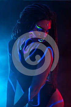 Cocky Girl with Dreadlocks in Ultraviolet neon light with Foggy Background. Bodyart