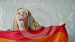 Cocky girl is showing her tongue while waiving LGBT pride flag