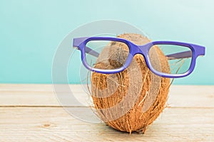 A cocnut wearing 3D glasses on blue background. Summer and trave concept