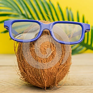 A cocnut wearing 3D glasses on blue background. Summer and trave concept