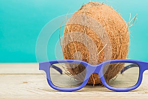 A cocnut wearing 3D glasses on blue background. Summer and travel concept