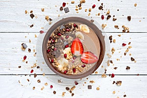 Cocoa banana protein smoothie bowl with chocolate granola, strawberry and pomegranate seeds