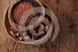 Cocoa beans and grated dark chocolate in old texured spoons bowl