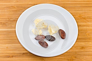 Cocoa beans and pieces of cocoa butter on a saucer