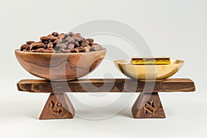 Cocoa beans in a wooden bowl and golden spoon on a wooden stand isolated on white background