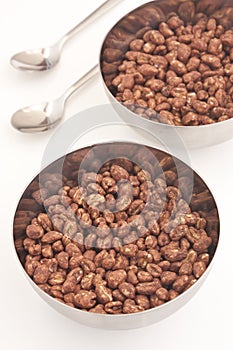 Cocoa coated puffed rice in metal bowls on white