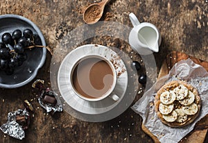 Cocoa, cracker with peanut butter, banana, flax and chia seed, grapes - snack, breakfast table. Cosy atmosphere breakfast on wood