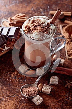 Cocoa with cream, cinnamon, chocolate pieces and various spices on a brown background