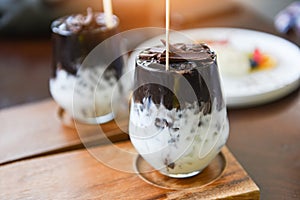 Cocoa drink and chocolate - tasty milk shake with ice cocoa in glass on wood background