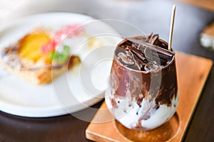 Cocoa drink and chocolate / tasty milk shake with ice cocoa in glass on wood background