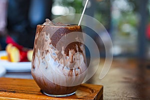 Cocoa drink and chocolate - tasty milk shake with ice cocoa in glass on wood background