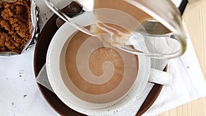 Cocoa drink is poured into cup, spoon on saucer. Natural delicious hot chocolate. Alternative healthy caffeine for breakfast.