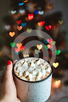 Cocoa with fried marshmallow. Christmas tree on background with bokeh heart shape