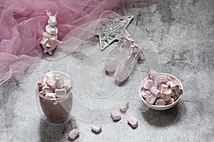 Cocoa with marshmallows, Christmas tree decorations and pink tulle on a concrete background.