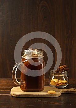 Cocoa with marshmallows in a glass high mug, on a wooden Board with cookies and cinnamon. On a dark background, vertically with