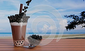 Cocoa Pearl Milk Tea, put black pearl or bubble jelly in a clear glass and brown straws placed on a wooden table and blur the sea