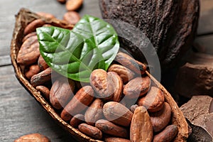 Cocoa pod with beans and leaves on table,