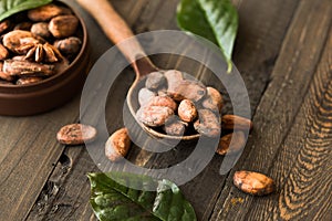 Cocoa powder and cacao beans on wooden background. Dark chocolate pieces crushed and aromatic herbs .