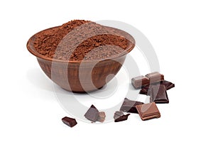 Cocoa powder in a clay plateau next to pieces of chocolate