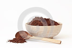 Cocoa powder in wooden bowl with wooden spoon