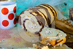 Cocoa roll with butter sliced on the table and a mug with red circles