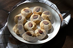Cococnut cookies, with cream cheese and almonds in plate on table with teatowel. Home kitchen sweets, baked. photo