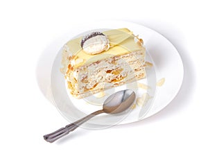 Coconut cake with peach on a porcelain plate on the white background, tea spoon and female hand