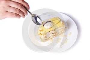 Coconut cake with peach on a porcelain plate on the white background, tea spoon and female hand