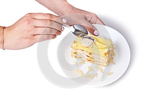 Coconut cake with peach on a porcelain plate on the white background, tea spoon and female hand