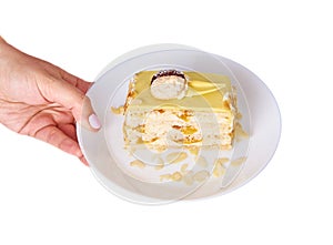 Coconut cake with peach on a porcelain plate on the white background, tea spoon and female hand