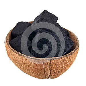 Coconut coal in half a coconut shell on a white background. Coconut charcoal cubes for hookah close-up.