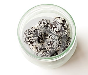 Coconut covered cacao date balls in a glass container isolated