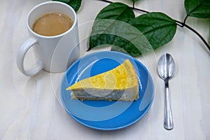 Coconut cream cake on blue plate, sweet dessert served for eating. Sweet dessert and cappuccino on table. Coffee break