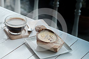 The Coconut Creme Brulee is sugary flavours and drink with hot americano black coffee on white wooden table background