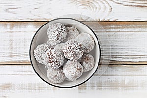 Coconut energy balls in a white cup.