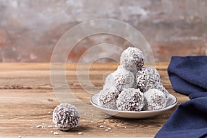 Coconut energy balls on a wooden tray, on a wooden table. Blurred background