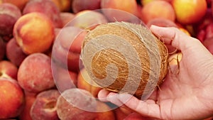 Coconut in a female hand on a background of peaches